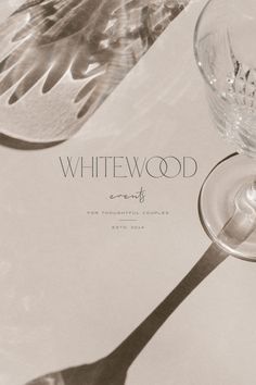 a wine glass sitting on top of a table next to an empty wine glass with the word whitewood written in it