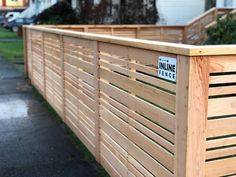 a wooden fence with a street sign on it's side in front of a house