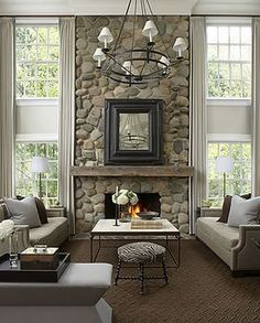 a living room filled with furniture and a fire place in front of a stone wall