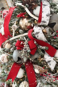 a christmas tree decorated with red and white ribbon, silver ornaments and pineconis