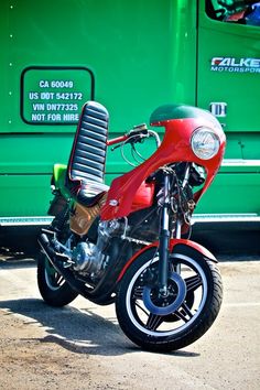 a red motorcycle parked in front of a green bus