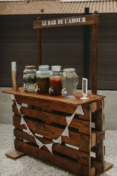 an outdoor bar made out of pallet wood with jars and spices on it, sitting outside