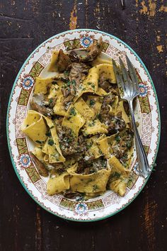 a plate full of pasta with meat and cheese on it, next to a fork