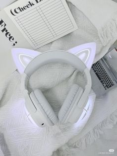 a pair of white headphones sitting on top of a bed next to a laptop