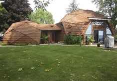 a large house with two round shaped roofs on top of it's grass covered yard