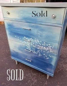 an old dresser painted with seagulls and the word sold on it's side