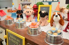 there are many stuffed dogs on display at this birthday cake table with cupcakes