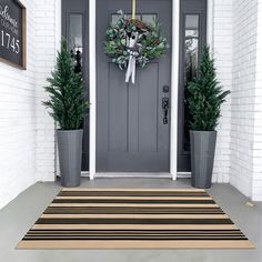 the front door is decorated with two potted plants and a wreath on it's side