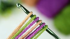 two crochet hooks are attached to the end of a green and purple hook