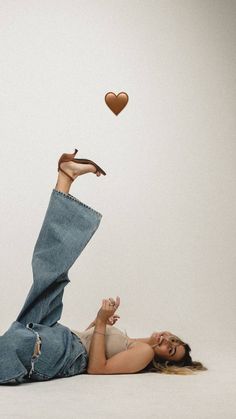 a woman laying on the ground with her legs up and hearts flying above her head