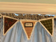 a blue and white striped curtain hanging from the top of a window sill with a name on it