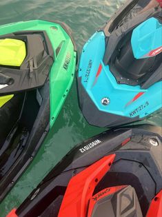 three jet skis are parked in the water near each other, one is blue and green