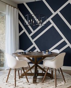 a dining room table with four chairs and a chandelier hanging from the ceiling