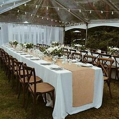 an outdoor tent with tables and chairs set up for a formal dinner or party in the grass