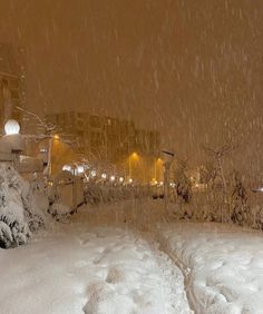 a snowboarder is going down a snowy hill in the city at night time