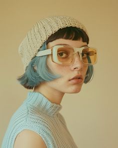 a woman with blue hair wearing glasses and a hat