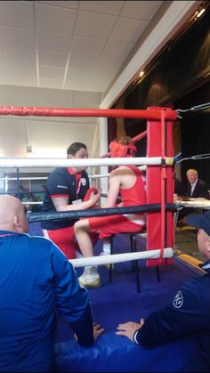 two boxers are sitting in the ring and one is on the ground with his head down