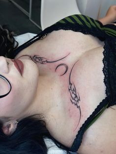 a woman with glasses on her head and tattoos on her chest is laying in bed