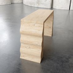 a wooden bench sitting on top of a cement floor in an empty room with concrete walls behind it