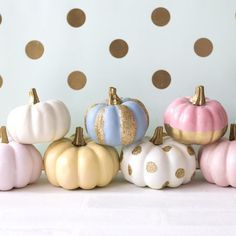 a group of painted pumpkins sitting on top of a white table next to a polka dot wall