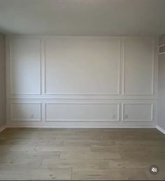 an empty room with white walls and wood floors