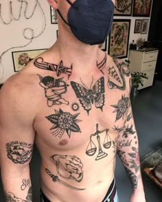 a man with tattoos on his chest wearing a face mask