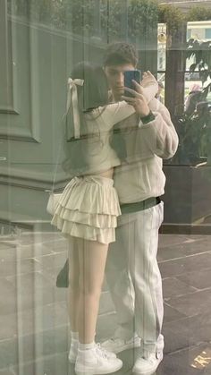 a man and woman taking a selfie in front of a store window