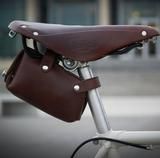 a close up of a bike handlebar with a brown leather bag on the seat