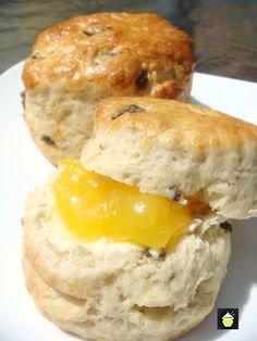 two biscuits with cheese on them sitting on top of a white plate next to each other