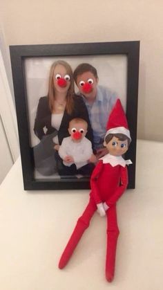 an elf with two red noses is posed in front of a photo frame while holding a baby