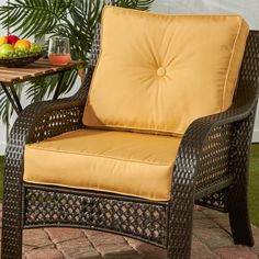 an outdoor chair with yellow cushions on a patio table and potted plant in the background