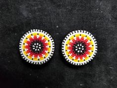 two small beaded buttons sitting on top of a black surface