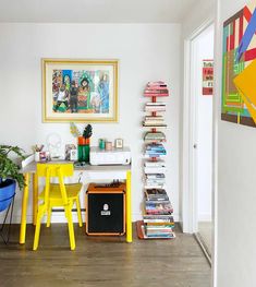 a room with two yellow chairs and a desk in front of a painting on the wall