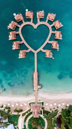 an aerial view of a heart shaped structure on the beach with boats docked in it