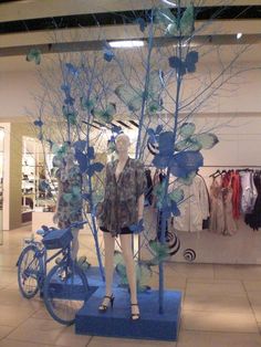 a mannequin is standing in front of a tree with blue leaves on it