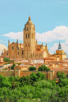 an old cathedral towering over a city with trees in the foreground and clouds in the background