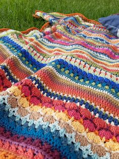 a crocheted blanket is laying on the grass