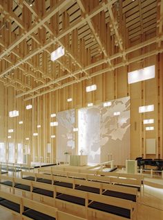 the interior of a large wooden building with rows of benches in front of a map on the wall