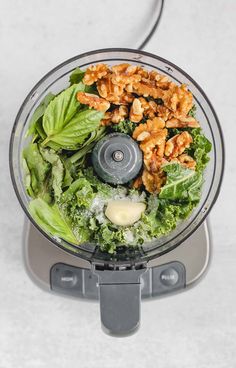 a food processor filled with lettuce, walnuts and other things in it