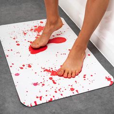 a person with bare feet standing on a bathroom floor covered in red and white paint