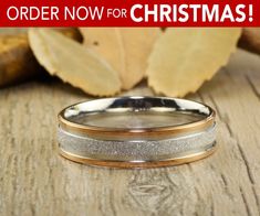 two tone gold and silver wedding bands on wooden surface with leaves in the back ground