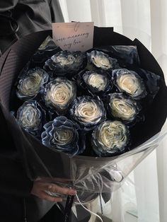 a person holding a bouquet of flowers with a note attached to the top of it