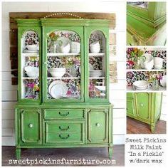 a green china cabinet with flowers painted on it