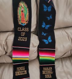 two black graduation sashes sitting on top of a white couch next to each other