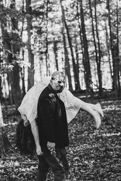 a man carrying a woman on his back through the woods in black and white photo