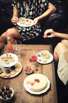 two women sitting at a table with desserts and drinks in front of their faces