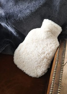 a white stuffed animal laying on top of a brown leather chair next to a black shirt