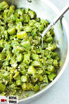 a pan filled with green vegetables and some silver spoons on top of the pan