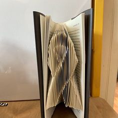 an open book sitting on top of a wooden table next to a white and yellow wall