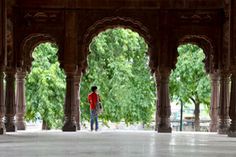 a man is standing under an archway in the middle of a building with trees on both sides